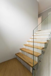 A wooden and concrete staircase with glass balustrade 